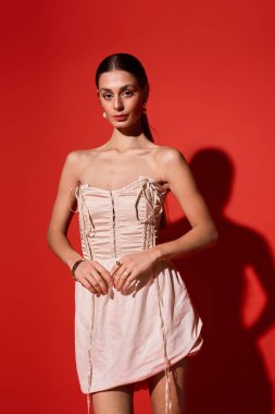 Genç bir kadın zarif bir elbise içinde ışıl ışıl bir cazibe ve moda anlayışı içinde duruyor..