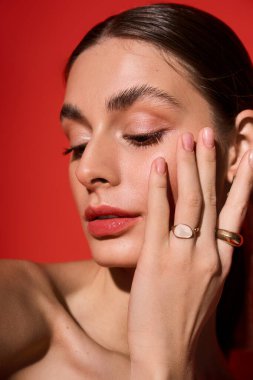 Büyüleyici bir kadın, kırmızı bir arka plana karşı zarafet ve çekicilik sergiliyor..