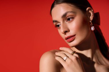 Zarif genç bir kadın göz kamaştırıcı mücevherlerini ve kusursuz makyajını yumuşak ışıkta sergiliyor..