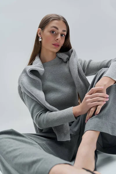 Çekici genç bir kadın, yumuşak ışıkta zarafetle poz verirken modern moda zarafetini sergiliyor..