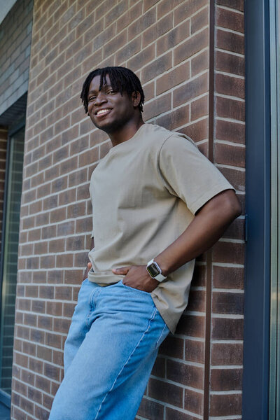 A handsome young man stands with confidence, smiling while enjoying a relaxed moment outdoors.