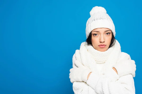 Jovem mulher descontente em chapéu de malha e luvas congelamento isolado em azul — Fotografia de Stock