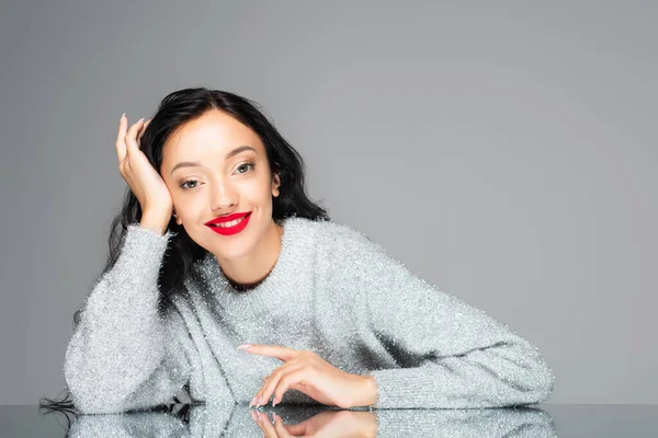 Happy brunette woman with red lips looking at camera isolated on grey — Stock Photo