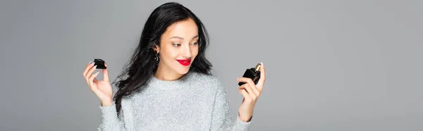 Mulher feliz com lábios vermelhos segurando garrafa com perfume isolado em cinza, banner — Fotografia de Stock