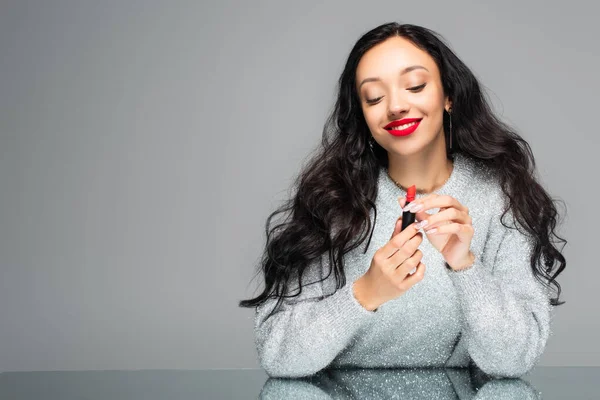 Happy woman with red lips holding lipstick isolated on grey — Stock Photo