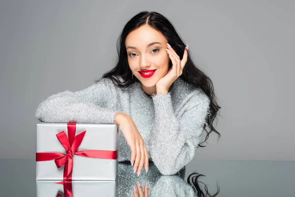 Femme heureuse avec lèvres rouges près boîte cadeau isolé sur gris — Photo de stock