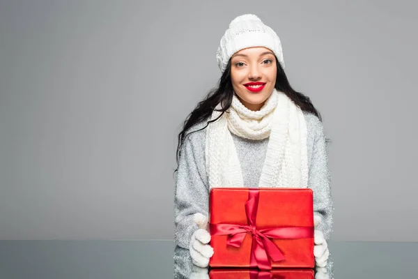 Happy woman in winter outfit holding present isolated on grey — Stock Photo