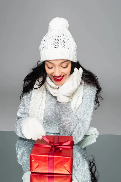 Happy woman in winter outfit looking at present isolated on grey — Stock Photo