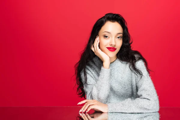 Jovem mulher satisfeita em suéter olhando para a câmera isolada no vermelho — Fotografia de Stock