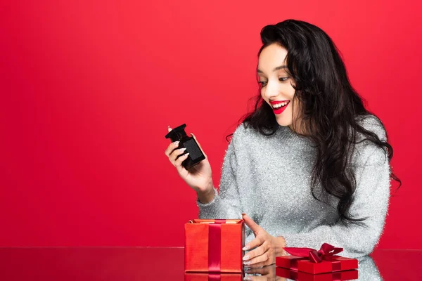 Felice donna bottiglia di tenuta con profumo vicino scatola regalo isolato su rosso — Foto stock