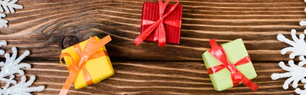 Top view of little gift boxes near snowflakes on wooden background, banner — Stock Photo