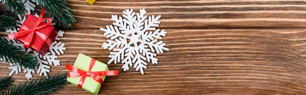 Top view of decorative snowflakes, little gift boxes and pine branch on wooden background, banner — Stock Photo