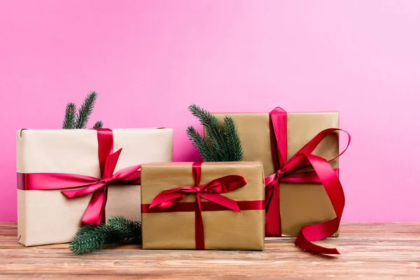 Wrapped gift boxes with pine branches on pink background, new year concept — Stock Photo