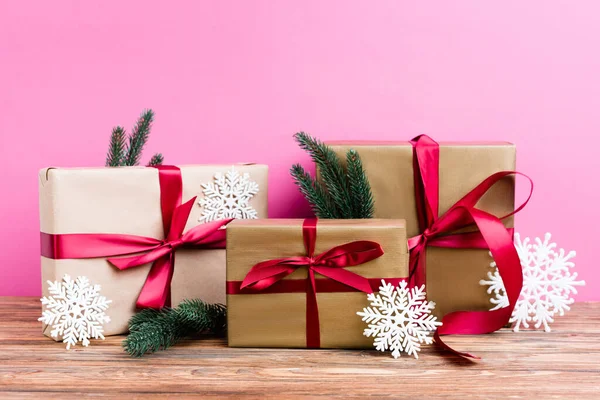 Gift boxes with decorative snowflakes and pine branches on pink background — Stock Photo