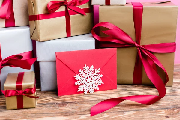 Vista cercana de cajas de regalo, sobre rojo y copo de nieve decorativo sobre fondo de madera - foto de stock