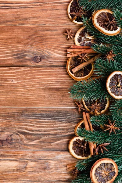 Draufsicht auf trockene Orangenscheiben, Anissterne, Zimtstangen und Tannenzweige auf braunem Holzgrund — Stockfoto