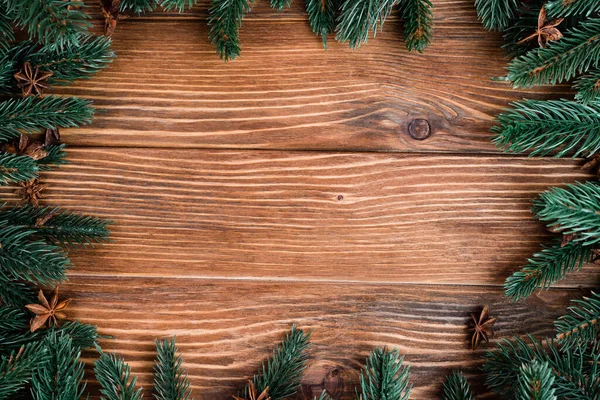 Flat lay with pine branches and anise stars on brown wooden background, new year concept — Stock Photo