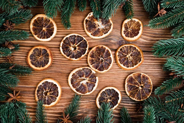 Flat lay with dry orange slices, pine branches and anise stars on brown wooden background, new year concept — Stock Photo