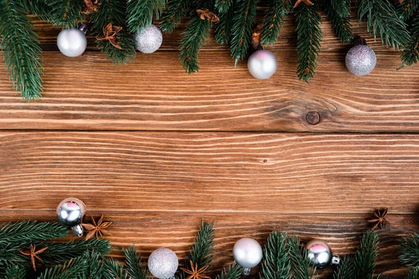 Flache Lage mit Tannenzweigen, Weihnachtskugeln und Anissternen auf braunem Holzgrund — Stockfoto
