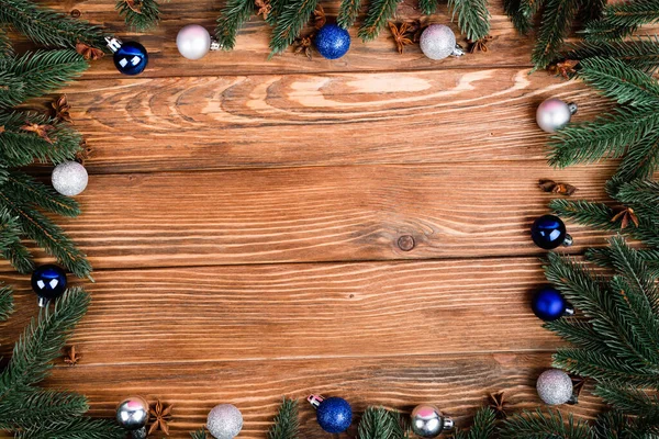 Flat lay com ramos de pinho, bolas de Natal e estrelas de anis no fundo de madeira marrom, conceito de ano novo — Fotografia de Stock