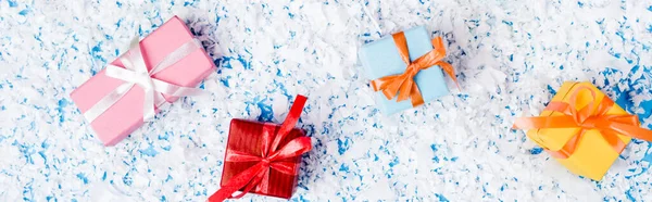Vista superior de pequeñas cajas de regalo con nieve artificial sobre fondo azul, pancarta - foto de stock