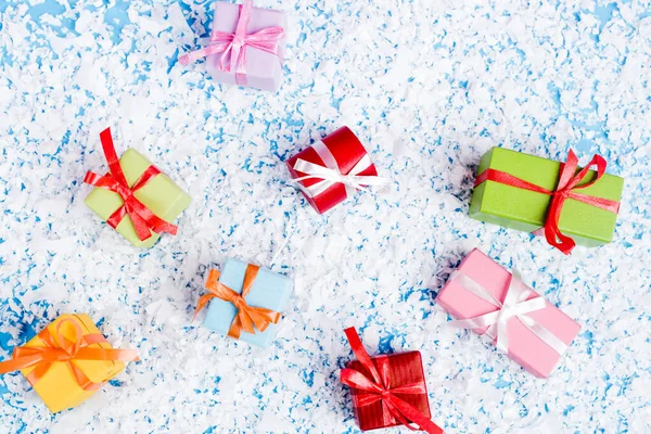 Top view of little gift boxes with artificial snow on blue background, new year concept — Stock Photo