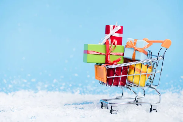 Livello di superficie del carrello della spesa con mazzo di piccole scatole regalo su sfondo sfocato, concetto di nuovo anno — Foto stock