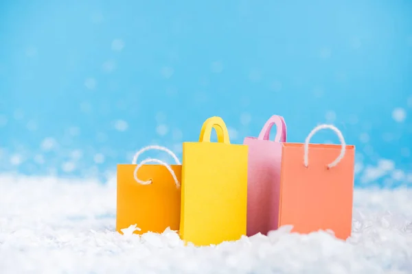Surface level of tiny paper bags with artificial snow on blurred background, new year concept — Stock Photo