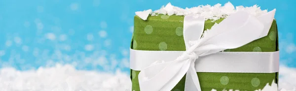 Close up view of little green gift box with artificial snow on blue background, banner — Stock Photo