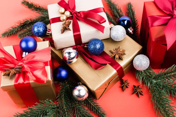 Gift boxes with baubles, anise stars and pine branches on red background — Stock Photo