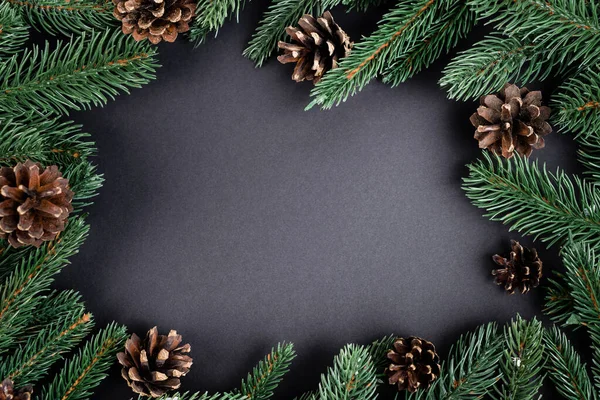 Flat lay with pine cones with fir branches on black background, new year concept — Stock Photo