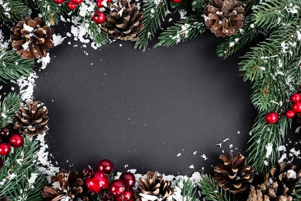 Posa piatta con pigne, perline rosse, rami di abete rosso e neve artificiale su sfondo nero, concetto di nuovo anno — Foto stock