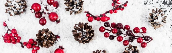 Top view of pine cones and branches with red beads on white textured background, banner — Stock Photo