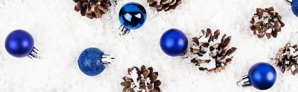 Vue du dessus des cônes de pin et des boules de Noël sur fond texturé blanc, bannière — Photo de stock