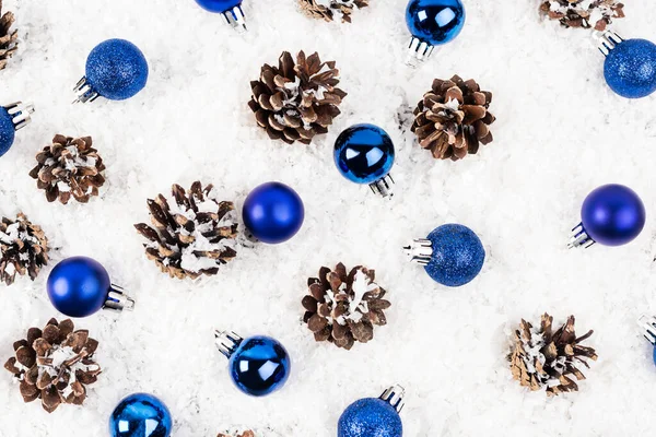 Flat lay with pine cones and christmas baubles on white textured background — Stock Photo