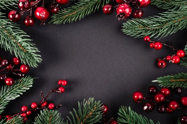 Draufsicht auf rote künstliche Beeren und Kiefernzweige auf schwarzem Hintergrund, Neujahrskonzept — Stockfoto