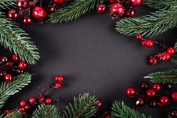 Top view of red artificial berries and pine branches on black background, new year concept — Stock Photo