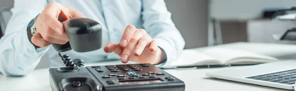 Cropped view of businesswoman with handset dialing number on landline telephone on blurred background, banner — Stock Photo