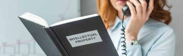 Vista ritagliata del libro con scritte di proprietà intellettuale con donna d'affari offuscata sullo sfondo, banner — Foto stock