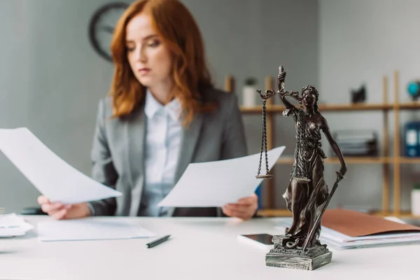 Themis Figur auf dem Tisch mit verschwommenem Anwalt mit Papierblättern auf dem Hintergrund — Stockfoto