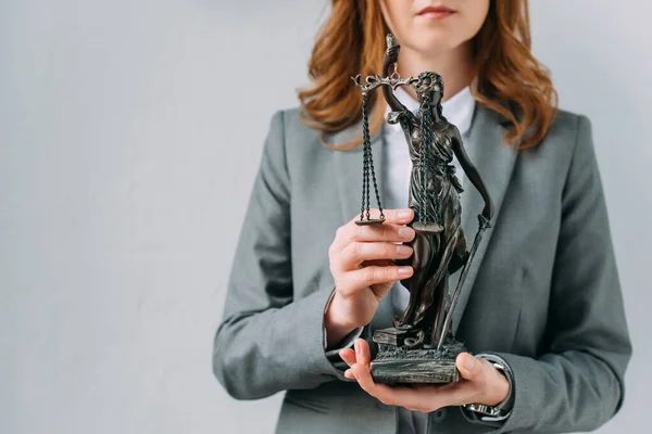 Cropped view of female lawyer holding themis figurine on grey — Stock Photo