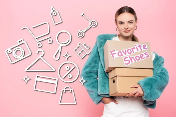 Femme heureuse dans des lunettes de soleil tenant des boîtes avec des chaussures préférées lettrage près de l'illustration sur rose — Photo de stock