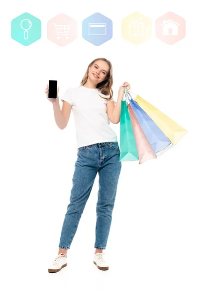 Довольная женщина, держащая смартфон с пустым экраном рядом с магазинами сумки и красочные иллюстрации на белом — стоковое фото