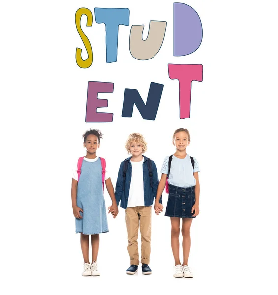 Blonde schoolboy holding hands with multicultural schoolgirls near student lettering on white — Stock Photo