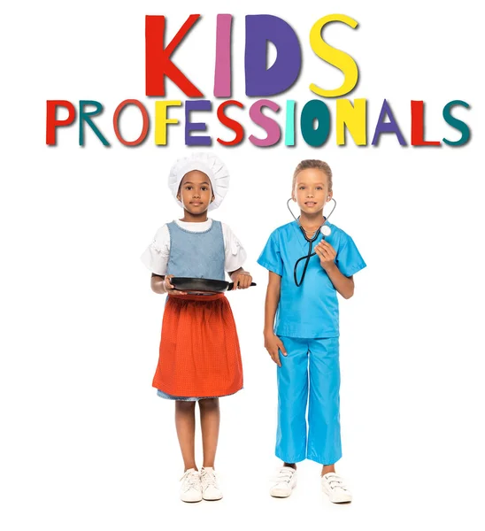 Multicultural girls in costumes of different professions standing near kids professionals lettering on white — Stock Photo