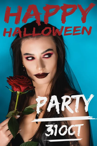 Mysterious young woman with black makeup in veil looking away near rose and happy halloween party lettering on blue — Stock Photo