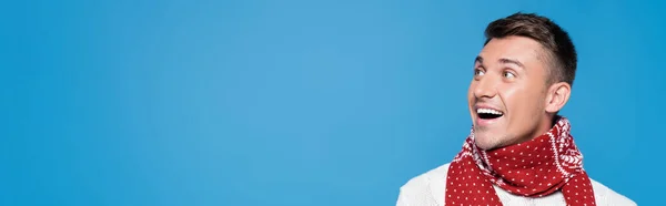 Excited young adult man in red scarf looking away isolated on blue, banner — Stock Photo