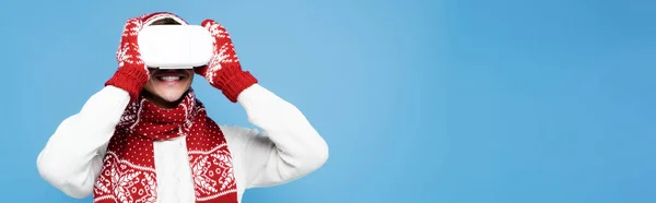 Hombre sonriente con ropa de abrigo, con auriculares vr aislados en azul, pancarta - foto de stock