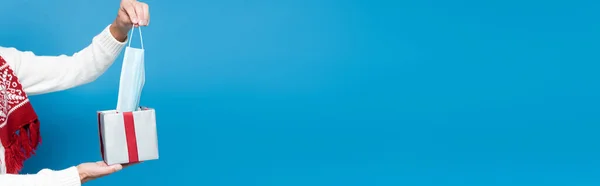 Cropped view of man taking medical mask from box isolated on blue, banner — Stock Photo
