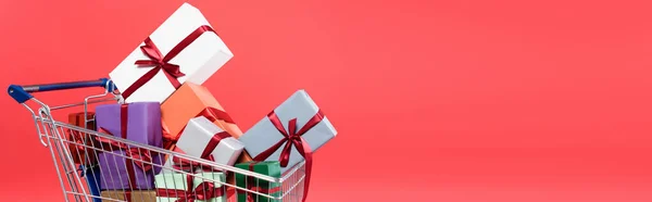 Presentes com arcos no carrinho de compras isolado em vermelho, banner — Fotografia de Stock